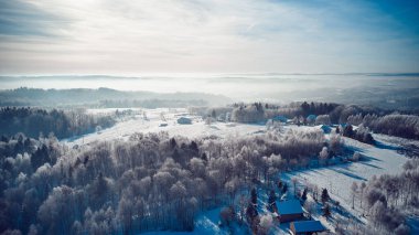 An aerial shot of a beautiful winter forest and houses