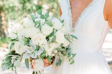 Beyaz gül buketini tutan gelinin seçici odak noktası.