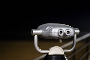 A closeup of the observation binoculars near the metal railing at night. Los Angeles, California, USA.