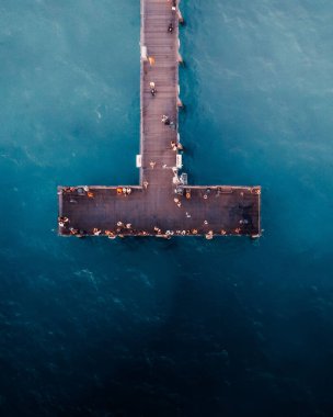 A top view of sea bridge in a clear blue sea and group of people on it