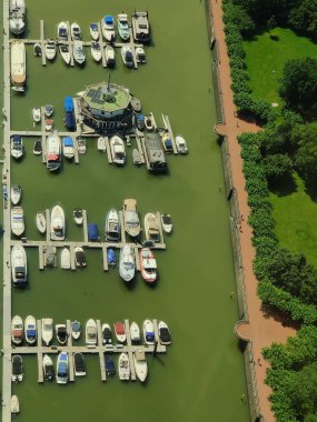 A vertical high angle shot of boats docked on a dirty green river surrounded by lush greenery