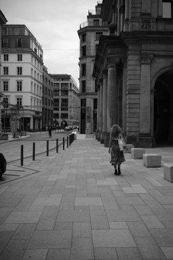 Güneşli bir günde meydanda yürüyen bir kadının gri pulu.