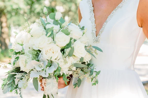 Beyaz gül buketini tutan gelinin seçici odak noktası.