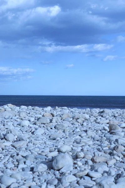 在蓝色 多云的天空下的一个岩石海滩的垂直镜头 — 图库照片