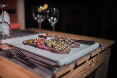 Kızarmış patates, domates ve soğanlı bir tabak et.