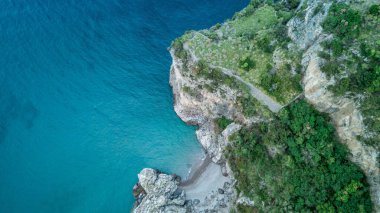 An aerial top view of the blue sea against rocky Amalfi coast covered with greenery in Italy