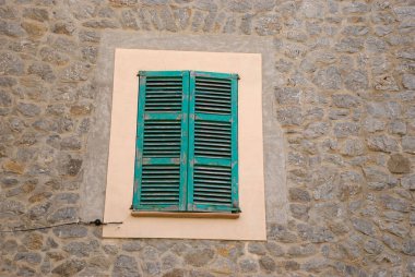 Closed green shutters on rustic old stone house on Mallorca, Spain - Baleares