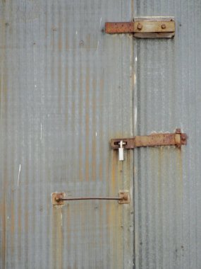 A vertical closeup of the locked rusty metal door.