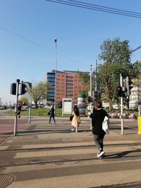 A vertical shot of people passing the street on a crossing with red lights on the Roosevelta street