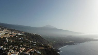 A scenic view of the Orotava Valley with Mount Teide in a fog by the ocean at sunrise, Canary Islands
