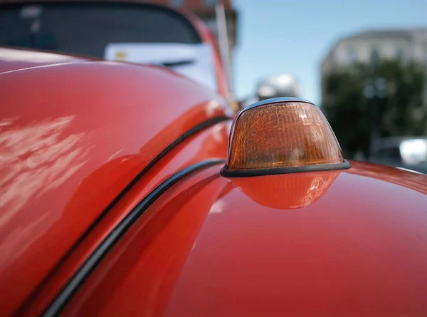A closeup of a turn signal of an old red VW Beetle car