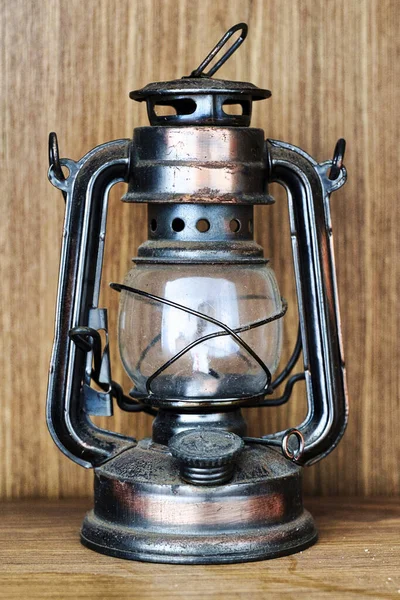 Vertical shot of a lantern lamp on a wooden table and a wooden background