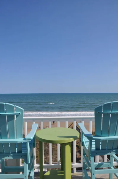 Vertical Shot Two Blue Chairs Green Table Overlooking Ocean — Stockfoto