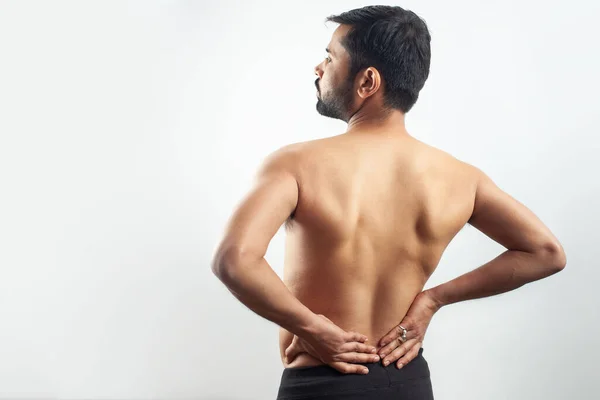 portrait of a young man holding his lower back pain point in white background