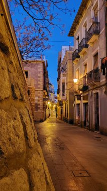 A vertical shot of an empty walkway in the evening with street lamps on in Sicily, Italy