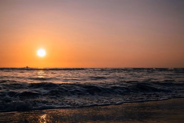 A beautiful view of splashing sea waves with the stunning sunset sky in the background