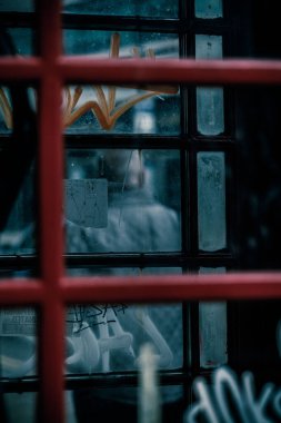 An urban scenery of a window behind a fence reflecting a male pedestrian