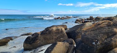 A scenic view of a rocky coast with clear blue water on a sunny day