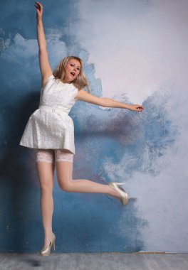 Stüdyoda poz veren beyaz çoraplı, uzun bacaklı, sarışın bir manken. Güzel gülümseme, inanılmaz bacak.