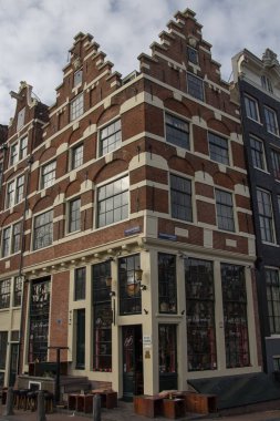 A vertical shot of an old brown building against a cloudy blue sky in Amsterdam, the Netherlands