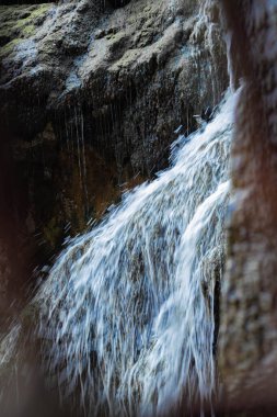 A closeup shot of a waterfall streaming through the rocks