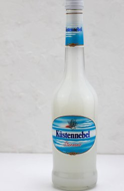 A vertical shot of a bottle of Kuestennebel liqeur with star anise on a white background