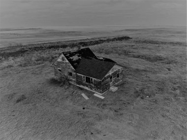 A grayscale of a rural house in a filed