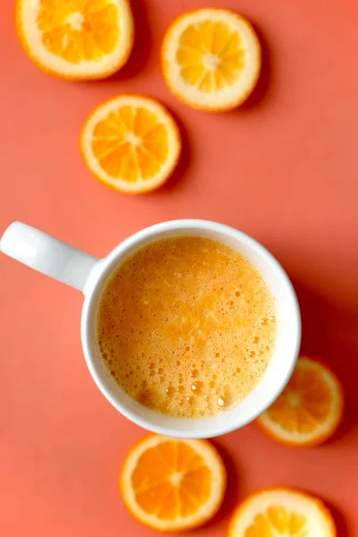 新鲜橙汁和一些桔子片的垂直顶视图 背景为金银花色 — 图库照片
