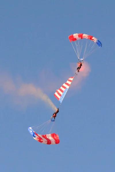 A vertical shot of two people parachuting connected with a large American flag