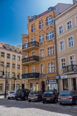 A row of parked cars in front of small shops on the Chwaliszewo street