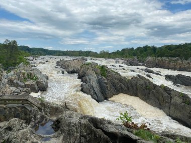 A breathtaking view of the mountainous flood river with a cloudy sky on the background