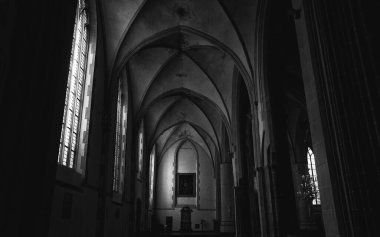 Pencerelerden gelen ışığın olduğu karanlık bir kilisenin iç manzarası.