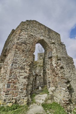 A low angle shot of arch Ruins of the Lowenburg castle in Monreal Eifel, Germany with a blue cloudy sky