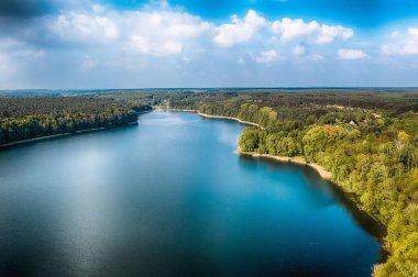 Rozalinowo Gölü 'nün mavi bulutlu gökyüzünün altında yeşil bir manzarayla çevrili insansız hava aracı görüntüsü.