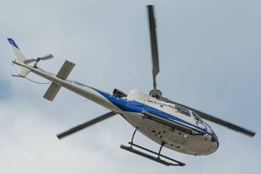 A low angle shot of a Helicopters Heli Dubai Tours Aerospatiale AS AS350 Ecureuil in the blue sky
