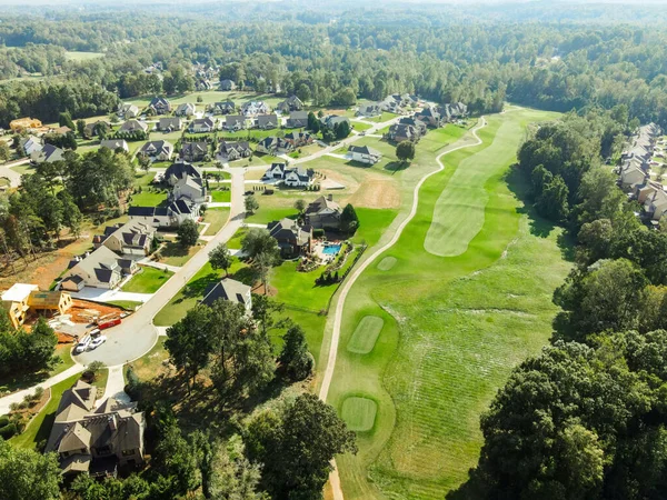 Drone view of trees and lawns and golf villas in a golf course on a sunny day