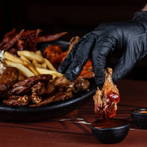 Hand Black Leather Glove Soaking Fried Chicken Leg Red Sauce — Stock fotografie