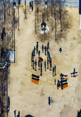 The vertical aerial shot of a group of people gathered  together in a park enjoying the weather