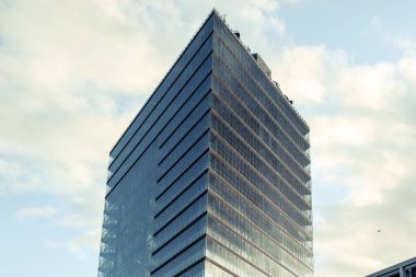 A low angle shot of a modern glazed building against a cloudy sky