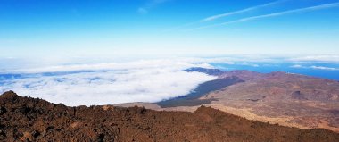 A panoramic mesmerizing view from a high point on a mountain over the clouds with blue sky