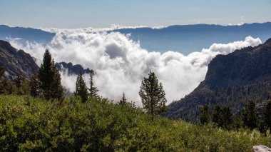 A beautiful view of meadows under the John Muir Trail mountain range with a cloudy sky in California