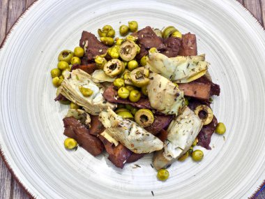 vegan dish based on seitan, artichoks, peas and olives with herbs and spices