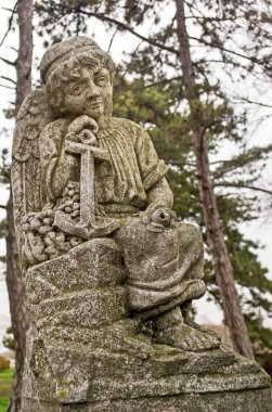 A selective focus shot of angel stone statue with an anchor