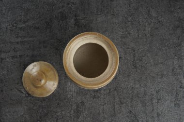 A small brown vintage pot on a dark background