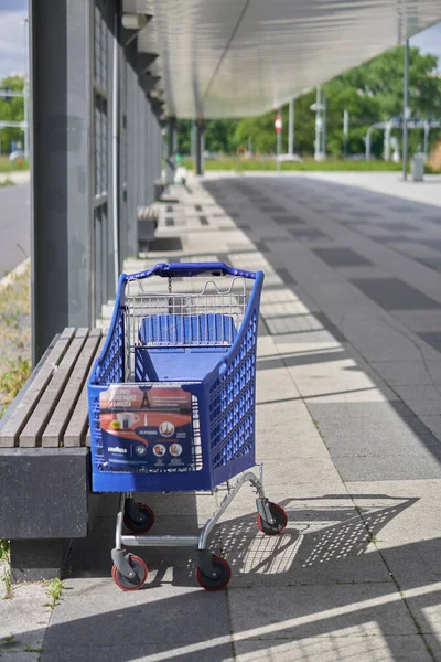 A vertical shot of an abandoned blue cart by a footpath of the Posnania shopping mall