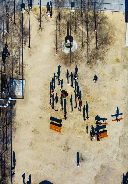 The vertical aerial shot of a group of people gathered  together in a park enjoying the weather