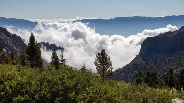 A beautiful view of meadows under the John Muir Trail mountain range with a cloudy sky in California