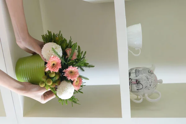 棚に花束を置いた花瓶を置く人の垂直ショット — ストック写真