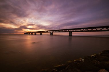 A breathtaking view of a bridge over the sea on a golden sunset sky background