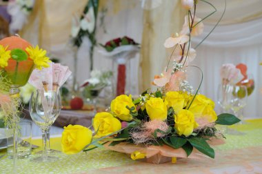 A close-up shot of an elegant table setting with glasses and yellow flower arrangements